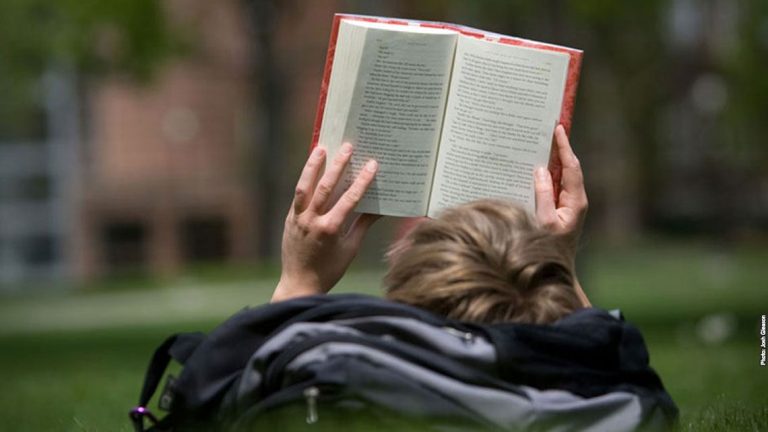 Student reading on lawn