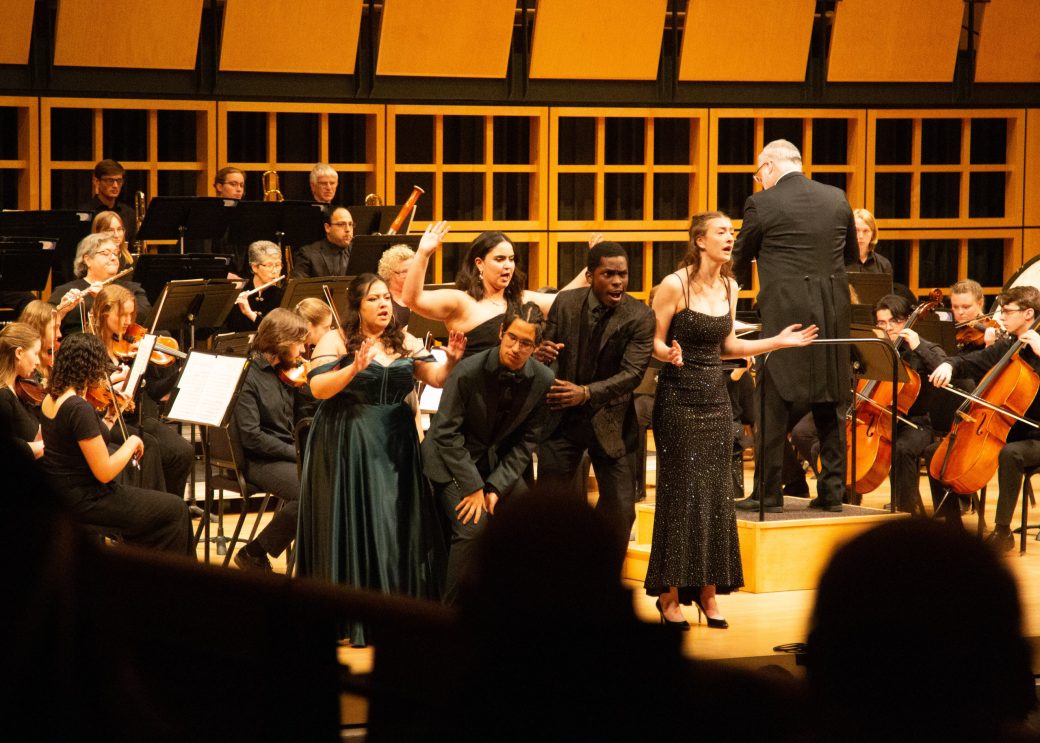 group of vocalists perform in front of orchestra