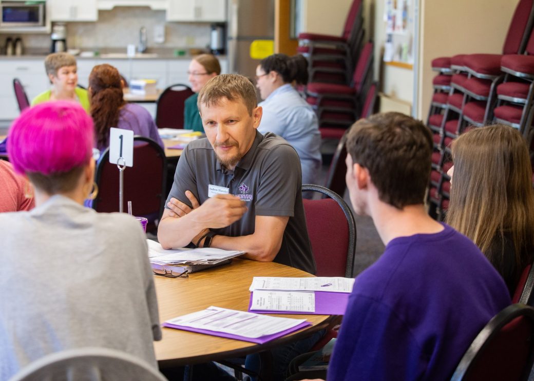 new students at tables with faculty and counselors for orientation