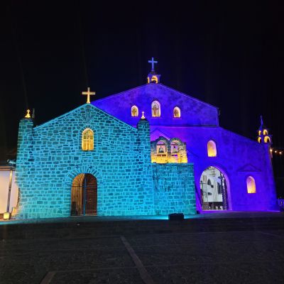 The expanded Iglesia de San Juan Bautista in the center square of San Juan la Laguna glows blue at night.