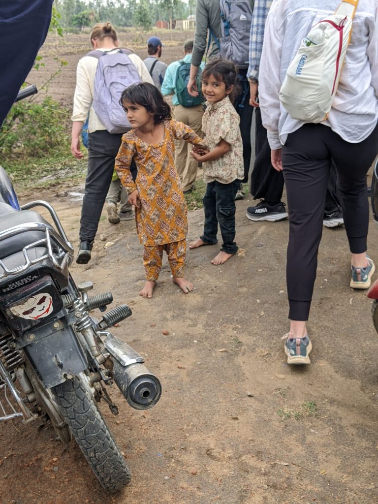 Two smiling young girls lead a group of students around.
