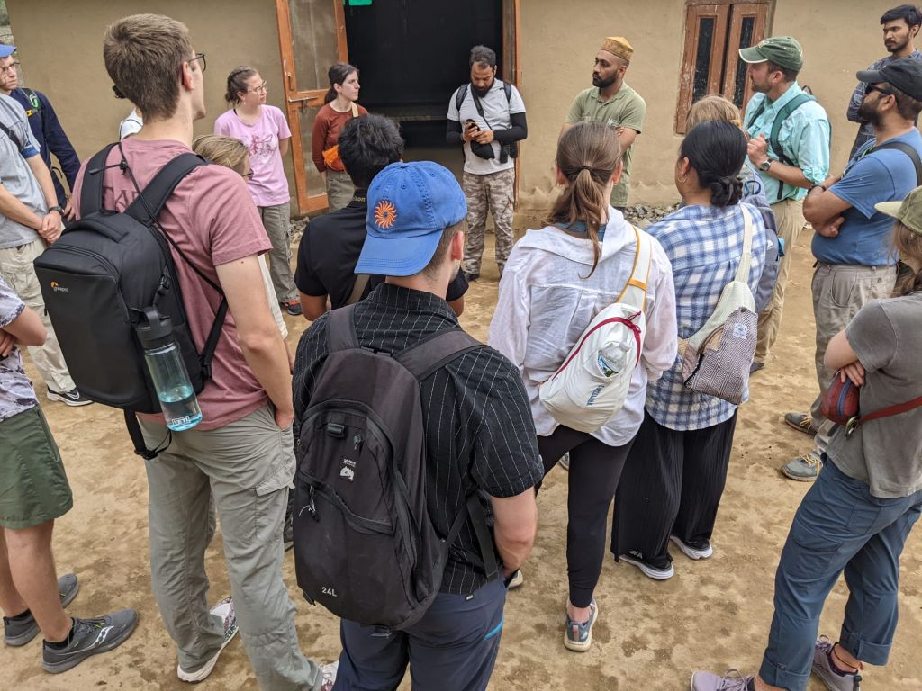 A group of students stands in a circle listening to locals.
