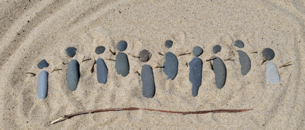 Small pebbles buried in sand made to look like people holding hands