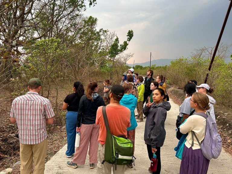 Students on a walk, with one flashing a peace sign to the camera.