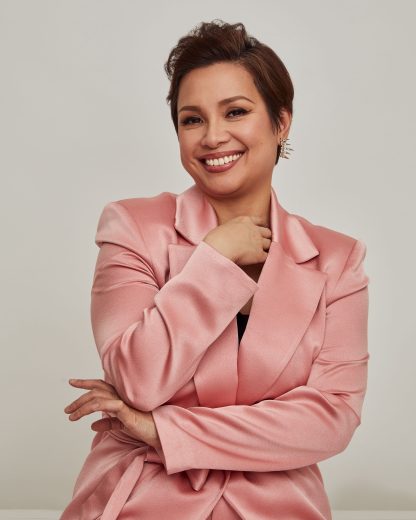 A headshot of a smiling Lea Salonga in a salmon blazer