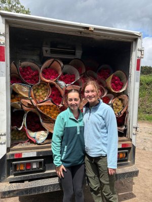 Two young women standing infront of a truck filled with flowers