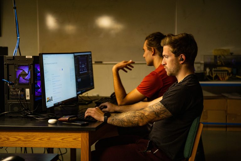 Two students sit at computers coding