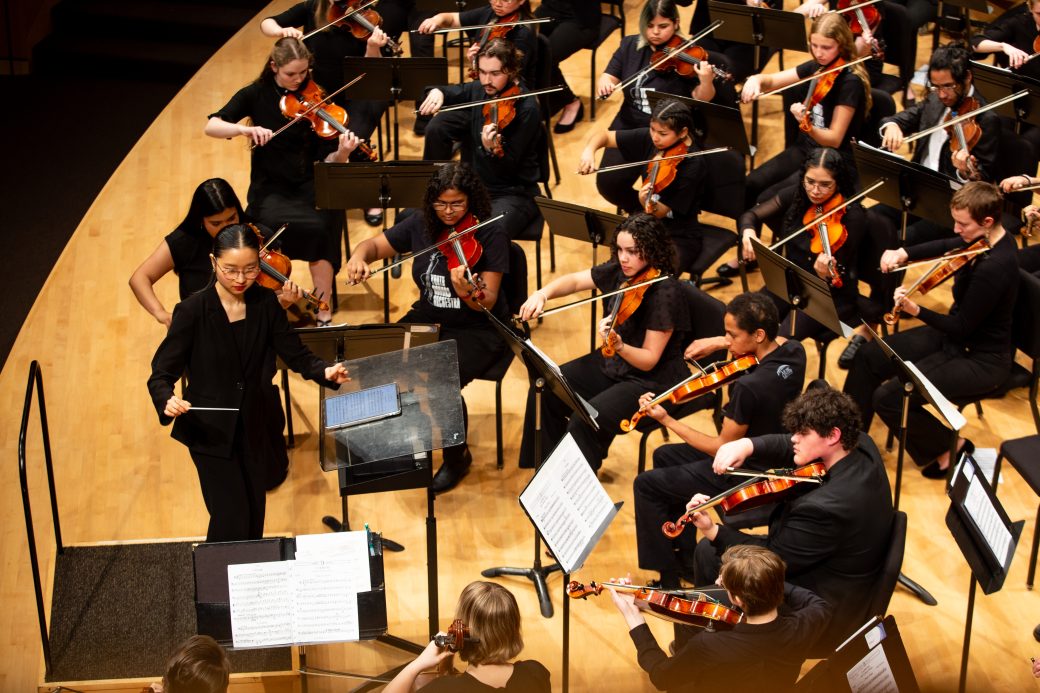 A GC student conducting a symphony orchestra concert