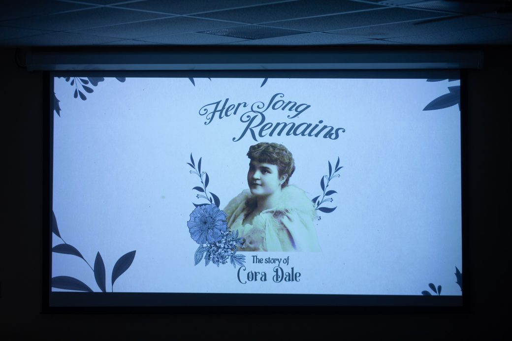 A screen showing "Her Song Remains: The Story of Cora Dale"
