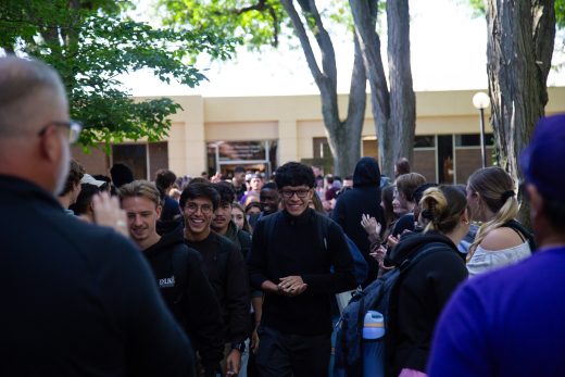 Students excitedly proceeding through a gauntlet of people clapping
