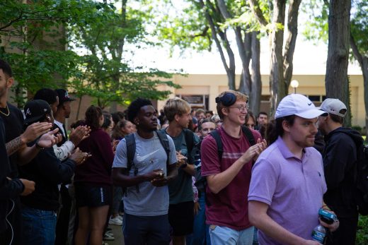 Students excitedly proceeding through a gauntlet of people clapping