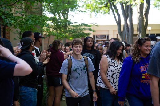 Students excitedly proceeding through a gauntlet of people clapping