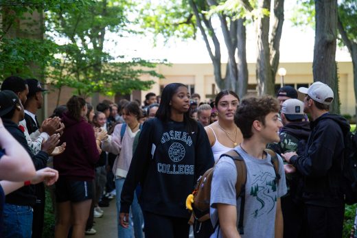 Students excitedly proceeding through a gauntlet of people clapping