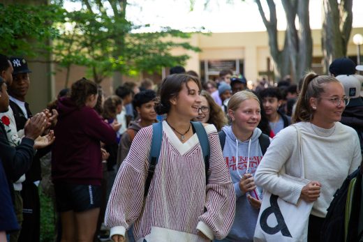 Students excitedly proceeding through a gauntlet of people clapping