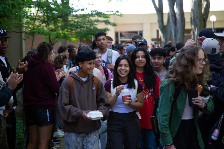 Students excitedly proceeding through a gauntlet of people clapping