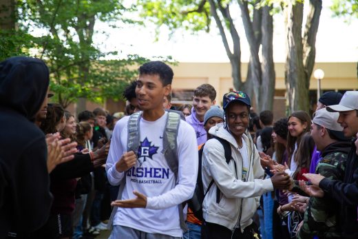 Students excitedly proceeding through a gauntlet of people clapping