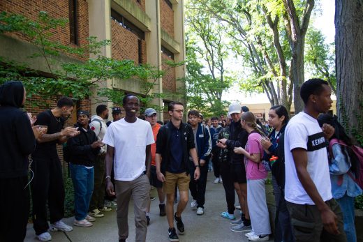 Students excitedly proceeding through a gauntlet of people clapping