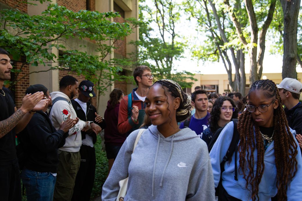 Students excitedly proceeding through a gauntlet of people clapping