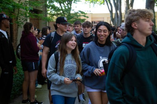 Students excitedly proceeding through a gauntlet of people clapping