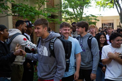 Students excitedly proceeding through a gauntlet of people clapping