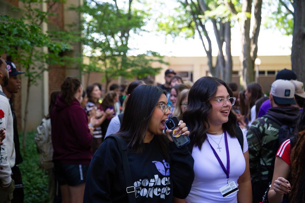 Students excitedly proceeding through a gauntlet of people clapping