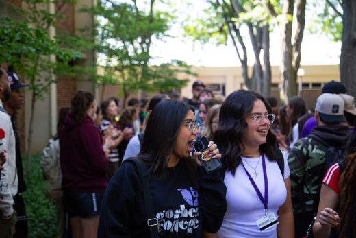 Students excitedly proceeding through a gauntlet of people clapping