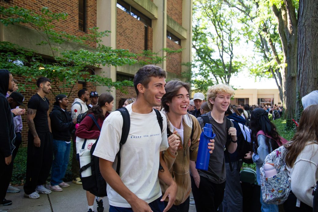 Students excitedly proceeding through a gauntlet of people clapping