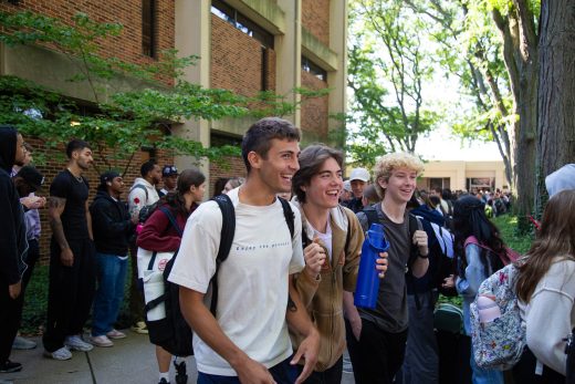 Students excitedly proceeding through a gauntlet of people clapping