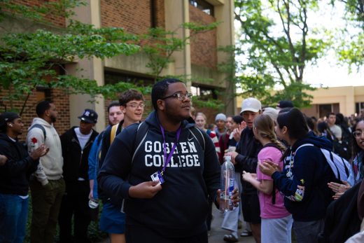 Students excitedly proceeding through a gauntlet of people clapping