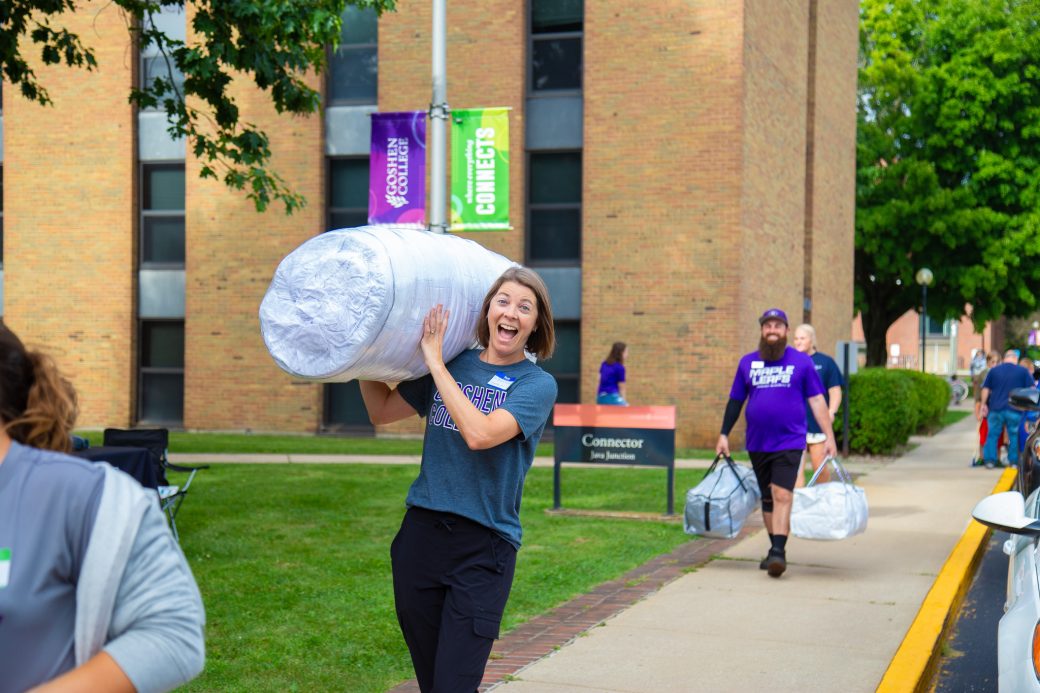 A person carries a large roll of bedding