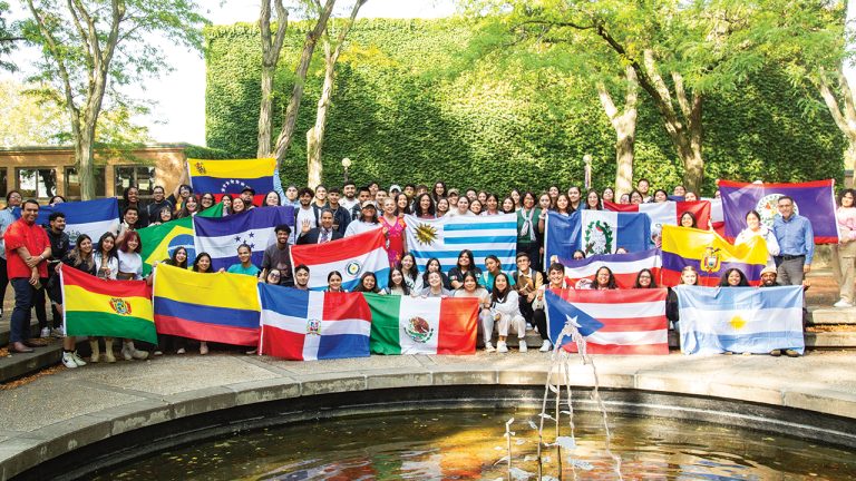 GC students hold up many different flags, representing their countries.