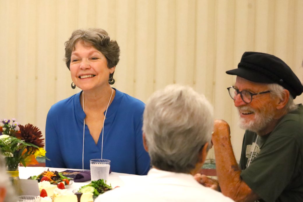 people sitting at a table, woman smiling.