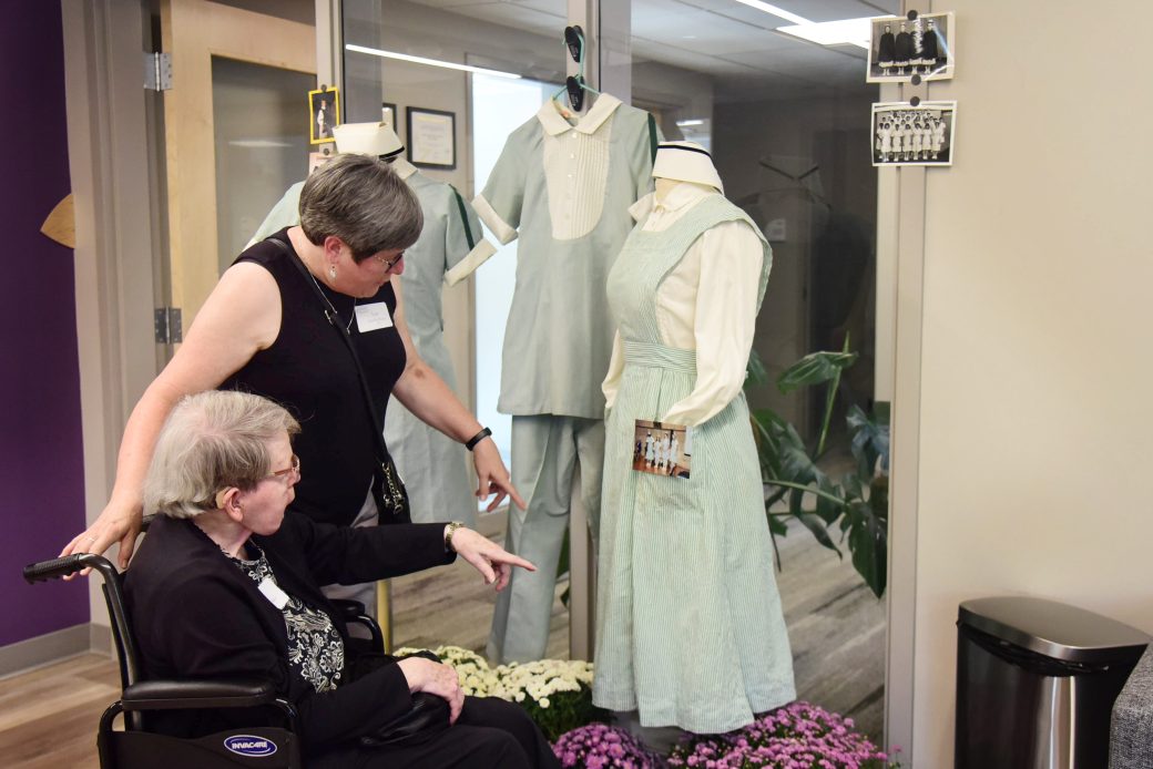 two women looking at the old nursing uniforms on display
