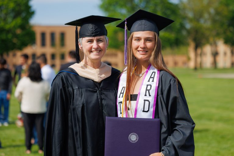 Graduate holding diploma with faculty member