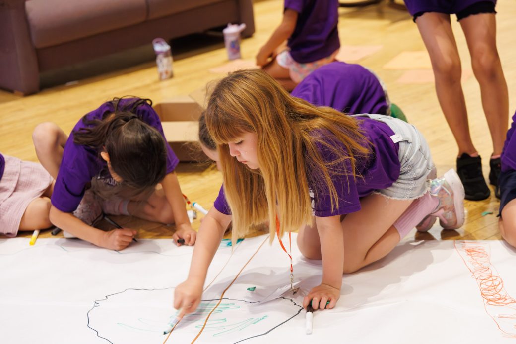 Young camper drawing on the floor