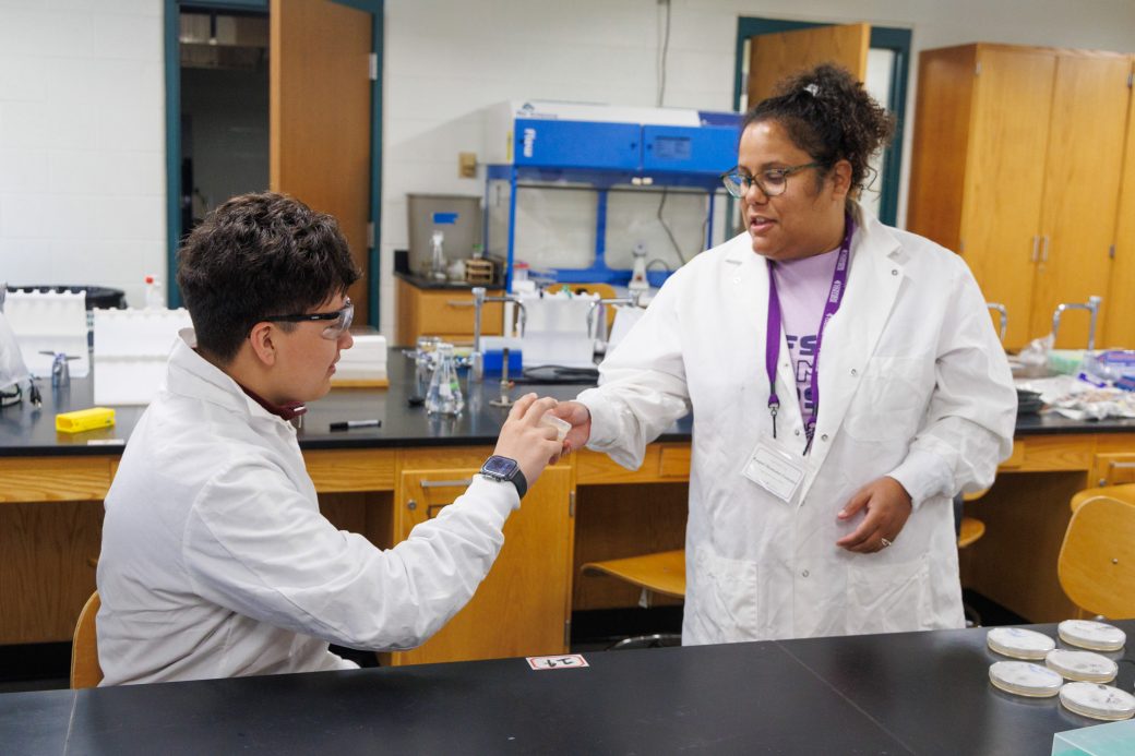 Teacher handing student project in science lab