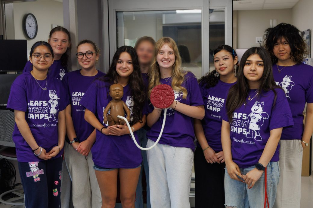Group of nursing students smiling while holding baby mannequin