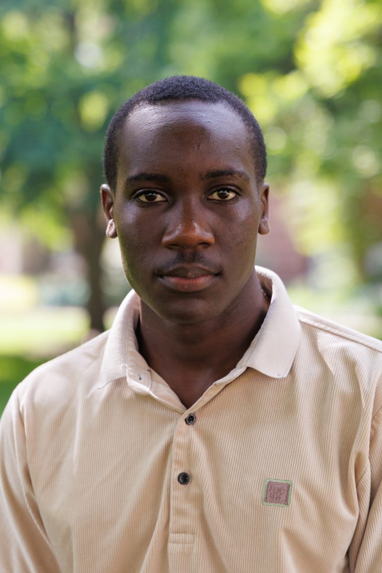 Professional headshot of Timothy Okiror wearing a beige polo shirt.