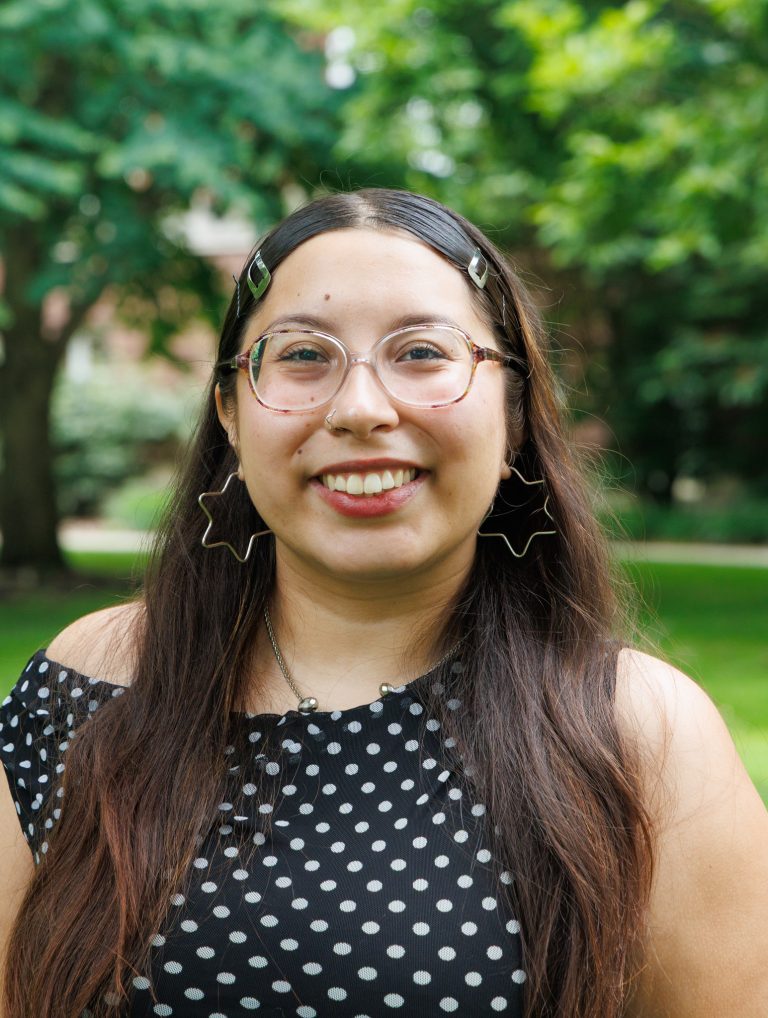 Professional headshot of Kat Columna wearing a black and white short sleeve polka dot shirt.