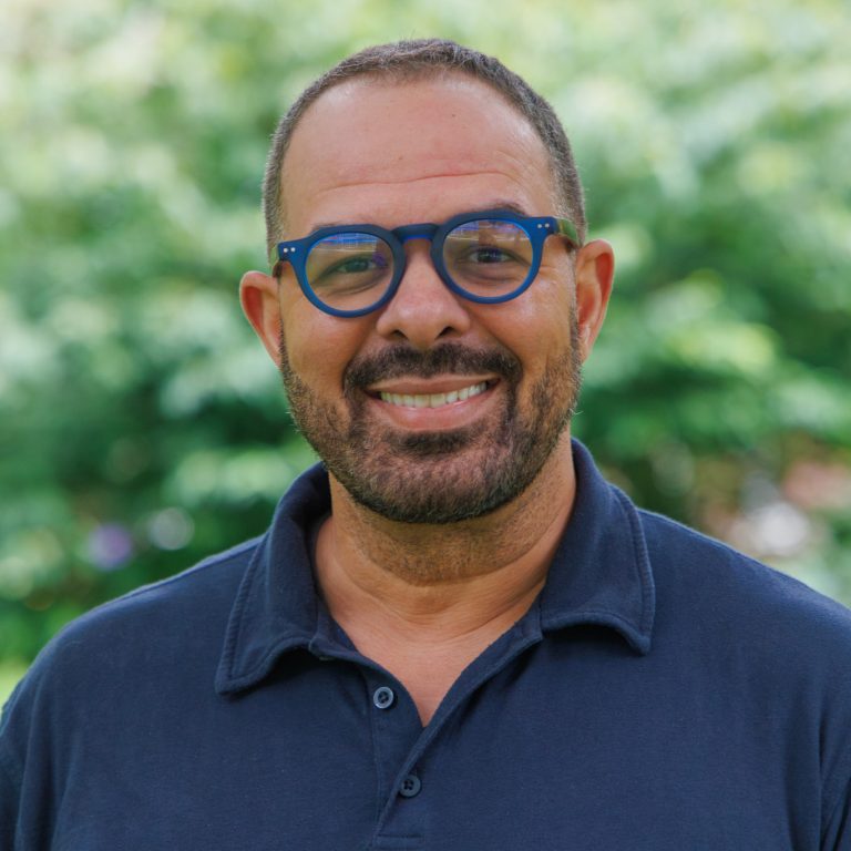 professional headshot of Mark Douglass taken in August 2026. He is outside looking straight ahead and wearing a dark blue polo.