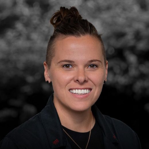 professional headshot of Katie Sowers wearing black blazer against grey backdrop.