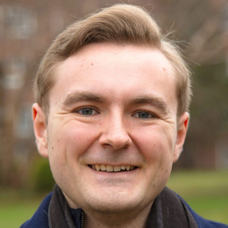 professional headshot of Joseph Kreider outside wearing a scarf and petticoat.