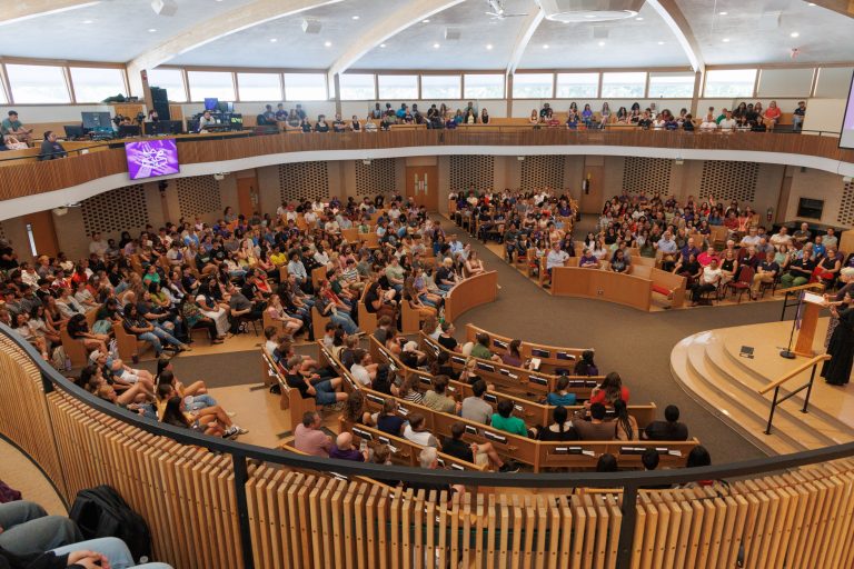 Wide angle of all of campus sitting in church-chapel for opening convocation