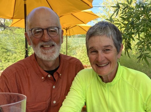 Stephen Kreider Yoder and wife, Karen Kreider Yoder outdoors under a sun umbrella.