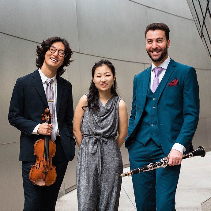 Trio Caspar in front of grey concrete building.