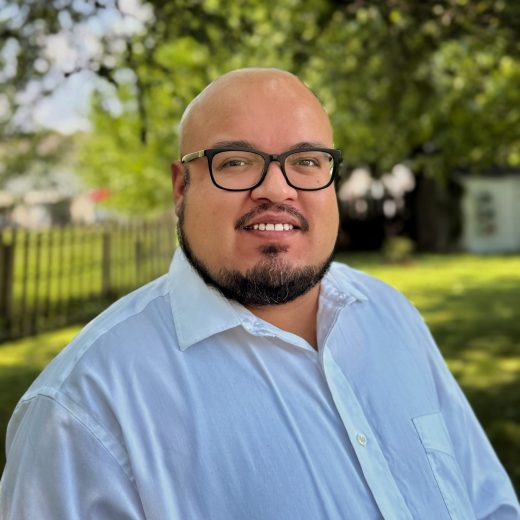 Edgar Saucedo outside smiling with a white-blue colored collared polo on.
