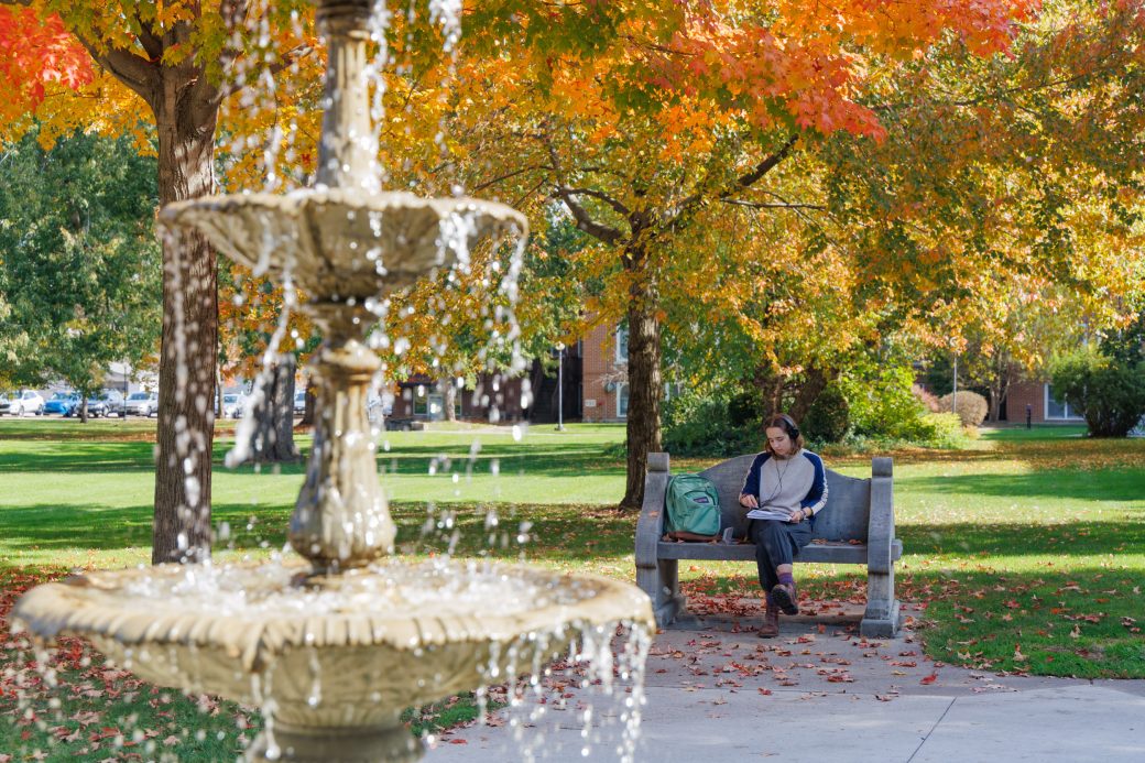 Student drawing by adelphian fountain on campus in fall