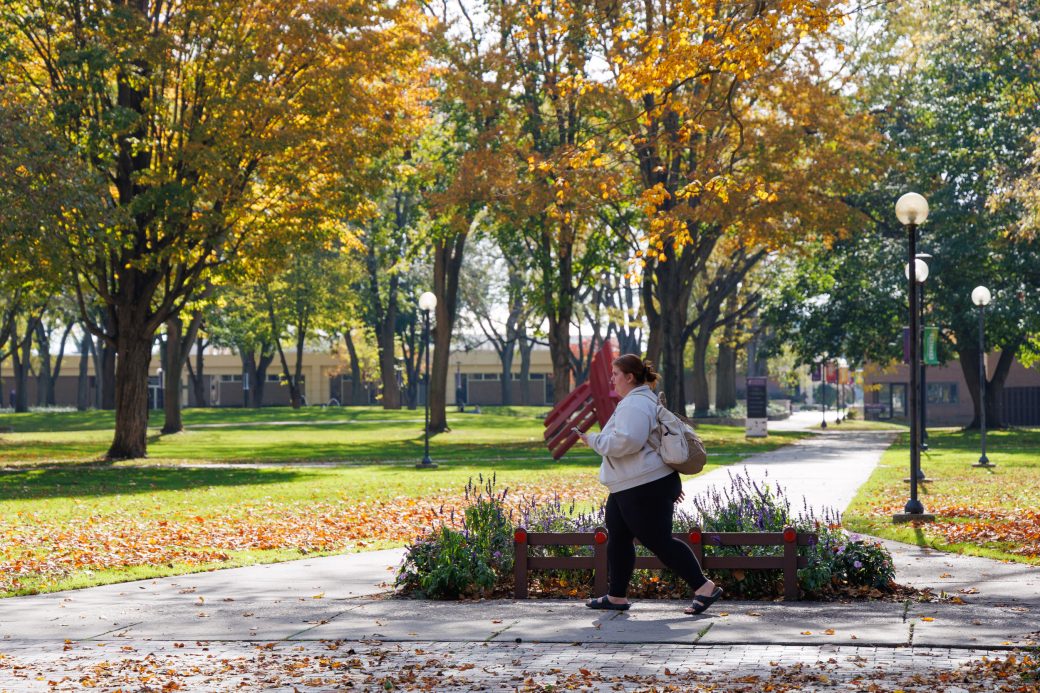 Student walking past shield in fall