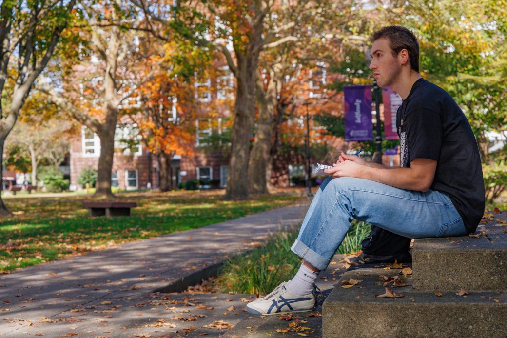 Student drawing outside on steps in fall