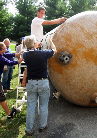 Sustainability Coordinator Glenn Gilbert instructs sohpmore Andrew Glick as they prepare to move the storage tank.